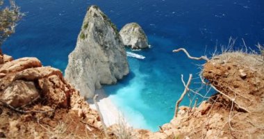 Kayalıklar arasında mavi denizde yüzen kayalık oluşum ve tur teknesi.