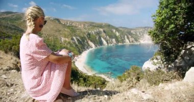 Dağın tepesinde gezgin bir kadın güzel deniz koyuna bakıyor manzaralı manzarayı kutluyor tatil macerasının tadını çıkarıyor doğa.