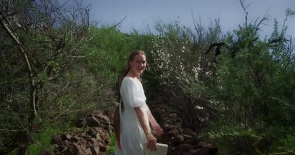 Камера Слідує Жінкою Мандрівницею Білому Платті Ходить Горах Квітучими Деревами — стокове відео