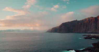 İspanya 'daki Tenerife, Kanarya Adaları' ndaki Los Gigantes kayalıkları yakınlarındaki sakin bir okyanus körfezi. Volkanik siyah kayalık plajı. Gün batımında deniz suyu manzarası dinleniyor..