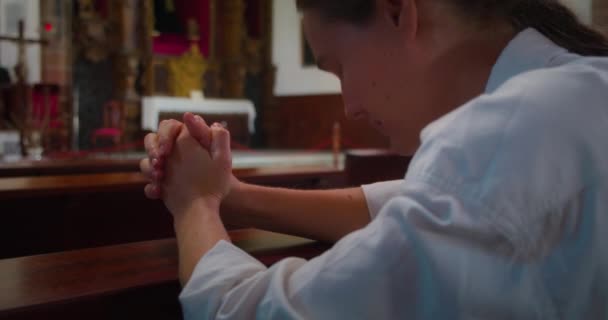 キリスト教徒の女性は 主の神殿でひざまずいて祈ります 教会で神を礼拝する宗教的な女の子 クローズアップスローモーション — ストック動画