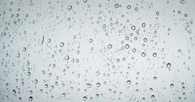 Sonbahar musonunda pencereye damlayan yağmur damlaları. Yağmurlu hava damlaları pencere camına vurur.