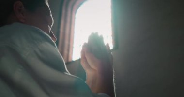 Kadın kilisede boyalı cam pencerenin yanında Tanrı 'ya dua ederken başını eğmiş. Kurtarıcı İsa 'ya dua etmek için katlanmış eller. Hıristiyanlık dini kavram.
