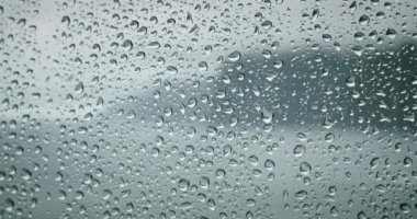 Pencere camına yağmur damlası. Dışarıda şiddetli deniz dalgaları var. Dramatik bulutlu hava ve yağmur. Sakinlik ve sakinleşme. Yavaş çekim sinematiktir..