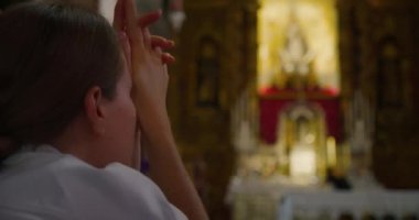 Hristiyan kadın Tanrı 'nın tapınağında diz çöküp dua ediyor. Kilisede Tanrı 'ya tapan dindar bir kız. Ağır çekimde yakın çekim.