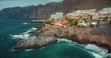 TENERİFE, Kanada Adaları, İspanya, 2023 Nisan: Kurtarma helikopteri kayalık kıyı şeridi yakınlarındaki fırtınalı bir okyanusun üzerinden uçar. Charco de Isla Cangrejo. Los Gigantes uçurumları. Yüksek kalite 4k görüntü.