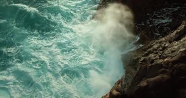 Okyanus dalgaları kayalık kıyıları yıkıyor. Kızgın deniz turkuazları köpüren ve yakın plan sinematik görüntüler saçan. Siyah volkanik kaya oluşumları..