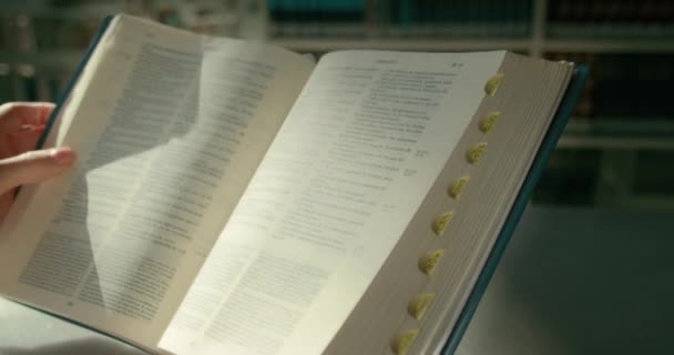 Hände Halten Ein Aufgeschlagenes Buch Der Universitätsbibliothek Warmes Licht Erhellt — Stockvideo