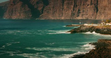 Tenerife, Kanarya Adaları 'ndaki Acantilados de Los Gigantes sahilindeki kayalıklar ve okyanus manzarası. Yavaş çekim deniz dalgaları, güneşli bir günde kayalık kıyılara çarpar..