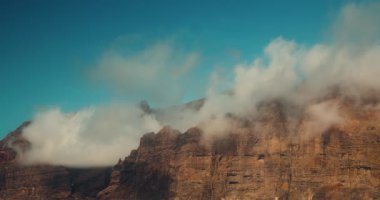 Tenerife kıyısındaki devasa volkanik dağların çorak tepelerinin görkemli manzarası. Mavi bulutlu güneşli gökyüzü. Sakin doğal manzara. Los Gigantes uçurumları.