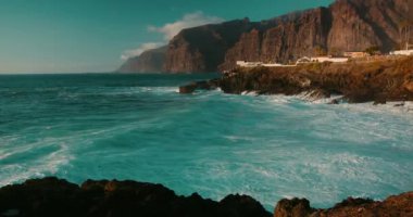 Büyük okyanus dalgaları Tenerife Adası kıyısındaki siyah volkanik kayalara çarpar. Derin mavi okyanus manzarası vahşi bir şekilde egzotik bir adanın kayalık kıyılarına sıçrıyor..