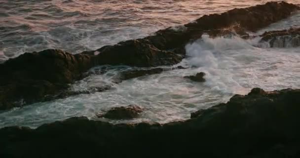 黄金の夕日の光で岩のビーチで砕ける白い泡の海の波 閉じる火山海岸の荒波の海の水を荒れ狂うアップ シネマティック ビュー — ストック動画