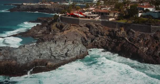 2023年4月スペインのカナリア諸島テネリフェ 救助ヘリコプターは岩の多い海岸線の近くの荒波の上を飛ぶ Charco Isla Cangrejo ギガンテスの崖 高品質4K映像 — ストック動画