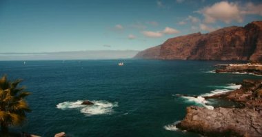 İspanya 'nın Tenerife Kanarya Adaları' ndaki Los Gigantes uçurumları. Volkanik kayalık plajı. Turist korsan gemisi, tekneler ve yatlar denizde yüzüyor. Popüler turizm merkezi Charco de Isla Cangrejo.