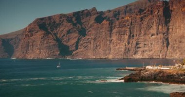 Tenerife, Kanarya Adaları 'ndaki Acantilados de Los Gigantes sahilindeki kayalıklar ve okyanus manzarası. Güneşli bir günde kayalık sahilde yavaş çekim dalgaları.