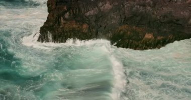 Şiddetli okyanus dalgaları köpürüyor ve kayalık volkanik plaja çarpıyor. Tenerife. Acantilados de Los Gigantes.