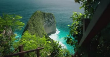 Tropikal kumsaldaki okyanus manzarası. Güçlü deniz suyu. Nusa Penida Endonezya kıyılarındaki yeşil orman.