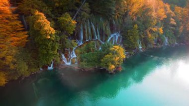 Plitvice Gölleri Ulusal Parkı Hırvatistan 'da altın sonbahar doğası. Renkli ağaçlar ve zümrüt yeşili tatlı suyla ormandaki şelale. Sonbahar mevsimi manzarası.