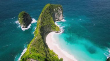 Nusa Penida adası Bali Endonezya 'da açık denizli rüya gibi tatil yeri Kelinking plajı. Dağ sırası el değmemiş beyaz kum ve mavi okyanus dalgaları üzerinde uzanıyor..