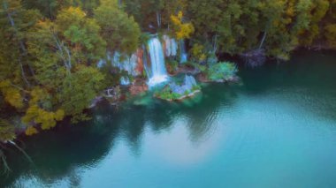 Karanlık orman manzarası ve hızlı akan bir şelale ile bir göle. Sonbaharda sahne sakin alacakaranlık doğası. Plitvice Lakes Ulusal Parkı Hırvatistan. Şelalenin havadan görünüşü zümrüt tatlı suya doğru akar.