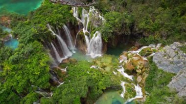 Yeşil ormanda güzel bir şelale, yukarıdan aşağıya doğru güzel bir manzara. Yaz dağı manzarası. Ünlü dönüm noktası ve turistik eğlence. Hırvatistan 'da Plitvice Lakes Ulusal Parkı.