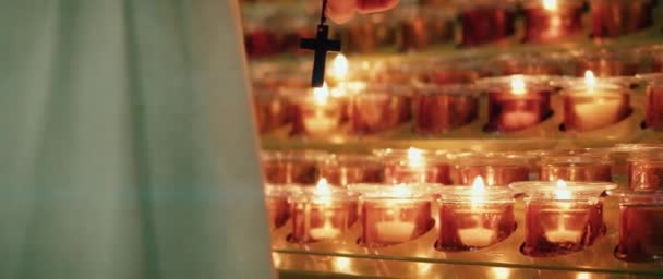 Человек Молится Держа Руках Религиозный Крест Зажигая Светящиеся Свечи Церкви — стоковое видео