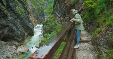 Kara Geçit 'i yağmurlu bir günde ziyaret eden turist kadın, Avusturya' daki Lammer Klamm 'da kristal berraklığında su akıyor. Alp manzarasında etkileyici bir gözetleme noktası..