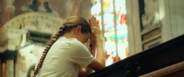 神殿でひざまずいて祈っている女性 誠実に信じる少女は カトリック教会で罪の赦しを神に祈ります — ストック動画