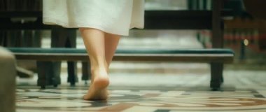 Çıplak ayaklı kadın kilise sıralarında yürüyor. Uzun elbiseli yetişkin bir kız diz çöküp dua ediyor. Ayaklara yakın çekim. Lord 'un yemeğinde geleneksel ayak yıkama..