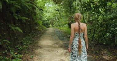 Bali, Nusa Penida, Endonezya 'daki Tembeling plajı ve ormanı yakınlarında ormanda yürüyen bir kadın turist. Yazın tropik doğa manzarası