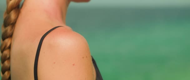 女性の肩に適用される日焼け止め 背景の海との行為 製品の使用および日焼け止めから皮を保護することの重要性 — ストック動画