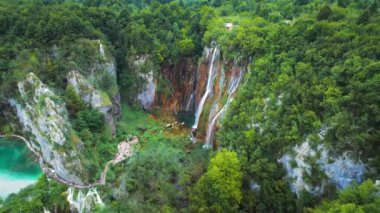 İlkbahar büyük şelale gür yaz ormanlarında yemyeşil uçurumun üzerinde şelale gibi akıyor. Su dereleri olan dağ gölü. Plitvice Ulusal Parkı Hırvatistan 'da yürüyüş yapan insanlar.