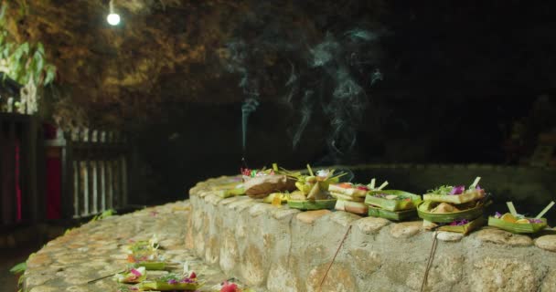 近景盘与供奉印度教精神和燃烧香气棒室外 巴厘岛努沙佩尼达的印度尼西亚文化 芬芳芬芳的烟熏和献给上帝的花瓣 — 图库视频影像