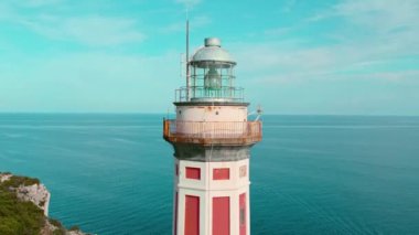 Açık mavi gökyüzüne karşı bir deniz fenerinin yakın çekimi. Beacon, İtalya 'nın Capri Adası' nda sakin bir denize bakan bir uçurumda duruyor...