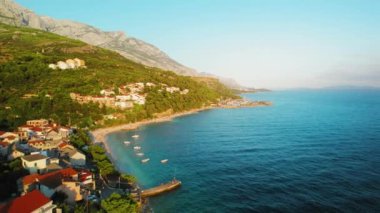 Batan güneşin yumuşak ışığında parlayan Makarska Riviera boyunca uzanan büyüleyici köy, dağ yamaçlarının yoğun yeşilliğinden Adriyatik Denizi 'nin berrak sularına kadar uzanıyor.