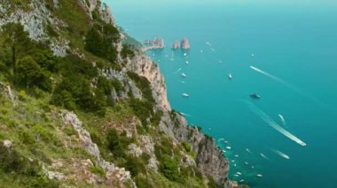 Capri sahillerinde okyanusları araştıran insanlar var. Nefes kesici manzara, ünlü Faraglioni kaya oluşumlarıyla engebeli kıyı şeridini ve masmavi suları kapsar. İtalya..
