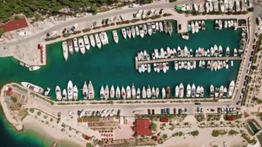 Yelkenli gemiler limanda macera bekliyor. Yat limanının yukarıdan görünüşü deniz yolculuklarına hazır teknelerle dolu..