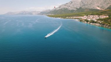 Sürat teknesi sakin Adriyatik Denizi 'nde köpüklü bir iz bırakıyor. Yukarıda, açık bir gökyüzünün altında kırmızı bir deniz aslanı yüzüyor...