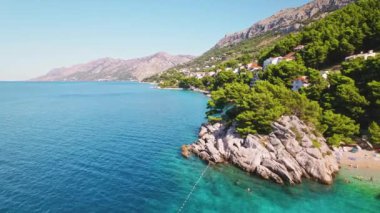 Huzur Denizi 'yle nefes kesici sahil şeridi. Sersemletici geniş açılı bir kıyı bölgesi, sakin mavi okyanus, yeşillik ve arka plandaki dağlar...