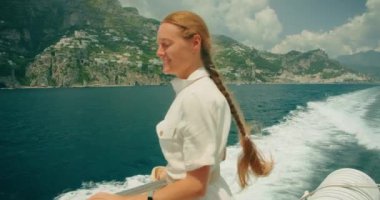 Positano, İtalya 'nın manzarasına hayran olan bir tekne gezisindeki yolcu. Kadın, Lattari Dağları 'na karşı kurulan katmanlı şehir manzarasına bakıyor...