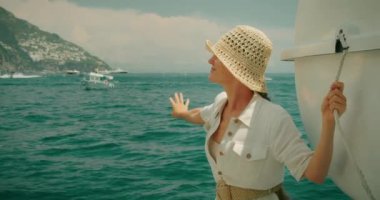 Neşeli bir kadın kolunu bir tekneden uzatıyor ve Tyrhenian Denizi 'nin enginliğiyle meşgul oluyor. İtalya 'da yaz tatili. Keyif yatından manzara..