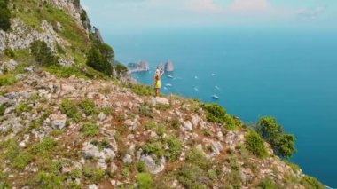 Sakin Gökyüzü Suları 'nın üzerindeki Rocky Arazisini Keşfeden Kadın. Bitki ve taş engebeli araziyi oluşturur, okyanus genişliği yayılır. Capri, İtalya..