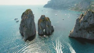 İtalya, Capri 'nin mavi sularından görkemli deniz yığınları yükseliyor. Tyrhenian Denizi 'ndeki doğal kaya oluşumları etrafında yüzen gemiler...