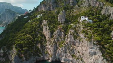 Yeşillik İtalya 'nın Capri Adası' ndaki engebeli uçurumları süslüyor. Dik kayalar üzerinde yeşil bitki örtüsü, sakin deniz genişliğine bakan, yatlar ve gemilerle benekli...