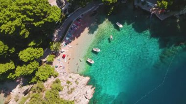 Hırvatistan 'ın Brela Punta Rata Sahili' nde güneş banyosu yapanlar ve tekneler kıyı şeridini dolduruyor. Rivieras cazibesi yaz havası ile güçlenir...