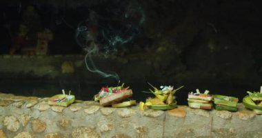 Hindu ruhlarına adaklar sunan tabakların yakın görüntüsü ve açık havada yanan aroma çubuğu. Bali Nusa Penida 'daki Endonezya kültürü. Aromatik tütsü dumanı ve çiçek yaprakları Tanrı 'ya getirildi..