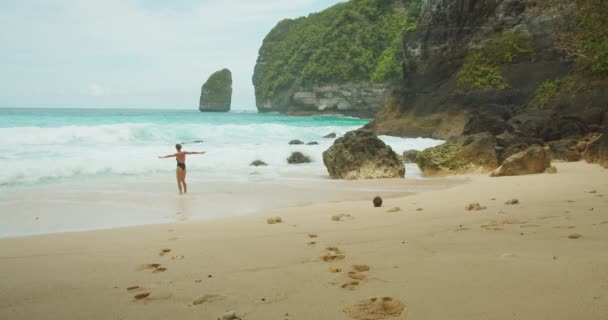 女人张开双臂 拥抱着温暖的阳光和清爽的大海 远处耸立着美丽的努沙 佩尼达悬崖 — 图库视频影像