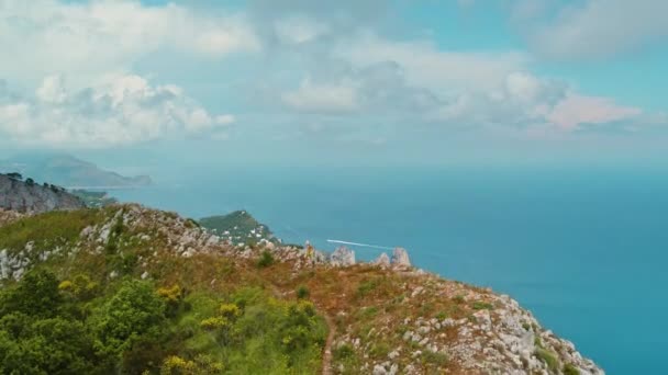 一个人俯瞰着卡普里 观察着浩瀚的蓝色大海和分散的船只 意大利妇女沿着危险的山脊沿着深蓝色的海水徒步旅行 — 图库视频影像
