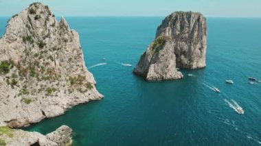 Serene deniz manzarası açılır. Huzurlu deniz, berrak bir gökyüzünü yansıtıyor. Capri kıyı kayalıklarının doğal görkemi su kayalıklarıyla...