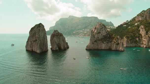 卡普里岛与法拉哥尼岩石笼罩在蔚蓝的水面之上 这是一个永恒壮丽的景象 小船滑行而过 在地中海阳光下高耸的大海堆中显得渺小 — 图库视频影像